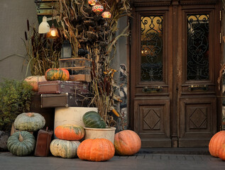 building entrance door decorated in autumn style. beautiful vintage lanterns, pumpkins and dried plants. Festive decor for fall season, Thanksgiving, Halloween holiday.