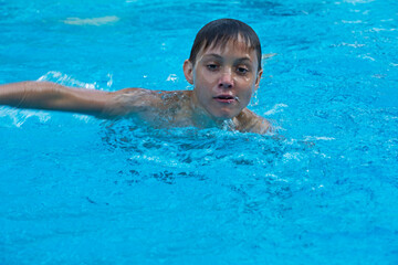 Fototapeta na wymiar happy boy is exercising in the pool. family holiday