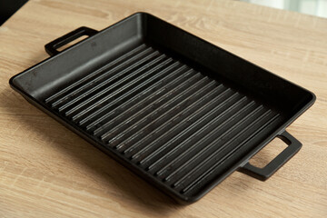 Empty black cast heavy iron grill pan on modern oak kitchen countertop