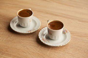 Traditional two turkish coffee in patterned white cup on oak coffee table