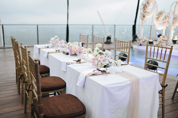 Romantic wedding party with stage on pool area. pale Blue white pink purple flowers accent. Modern wedding decoration, table settings outdoors for intimacy wedding dinner with family and friends on to