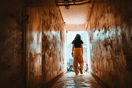 Woman Walking In A Narrow Hallway With Weathered Walls With Her Dog