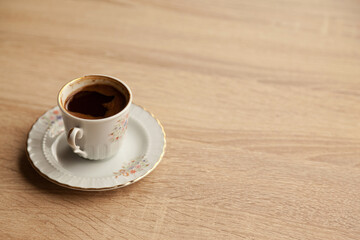 Traditional turkish coffee in patterned white cup on oak coffee table