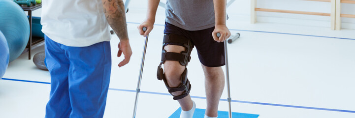 Man after car accident in an orthosis and on crutches learning t - 542452268