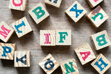 Alphabet letter block in word if and another letter on wood background