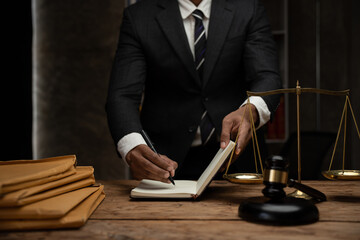 Close up lawyer businessman working or reading lawbook in office workplace for consultant lawyer concept.Lawyer working at table in office, focus on scales of justice