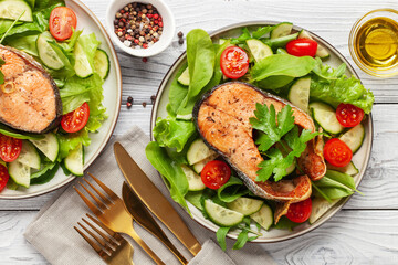 Fresh vegetable salad and baked salmon in a plate on the table. Mediterranean diet concept. Top view