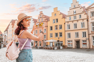 Fototapeta na wymiar Travel blogger takes photos on the camera of smartphone of the Osnabruck historical houses building in old town market square, Germany