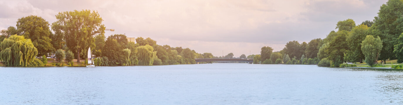 Scenic panorama of Aasee lake or pond with sailing boat in Munster city park. Leisure and recreation with yacht or sailboat