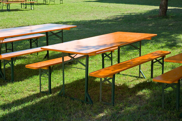 Wooden picnic table on a green meadow in a public park with trees