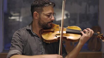 Adult bearded luthier playing hand crafted violin