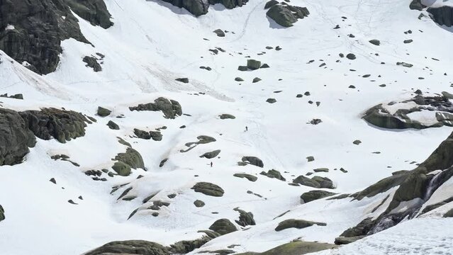 People freeriding down rocky slope of snowy mountain