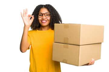 Young african american woman moving to other house while picking up a box full of things isolated cheerful and confident showing ok gesture.