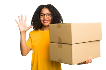 Young african american woman moving to other house while picking up a box full of things isolated smiling cheerful showing number five with fingers.