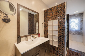 Bathroom with square framed mirror, dark wood cabinet and dark tiled shower cabin