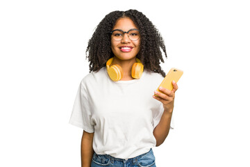 Young african american woman listening to music with yellow headphones isolated happy, smiling and...