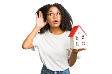 Young african american woman moving to a new home while picking up a box full of things isolated trying to listening a gossip.