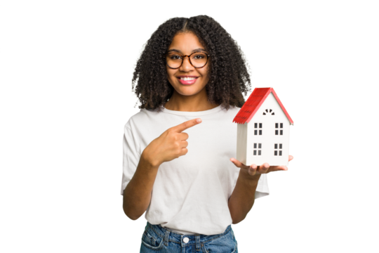 Young african american woman moving to a new home while picking up a box full of things isolated smiling and pointing aside, showing something at blank space.