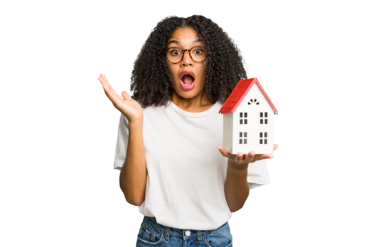 Young african american woman moving to a new home while picking up a box full of things isolated surprised and shocked.