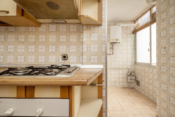 Corner of an old kitchen with dirty wooden cabinets and matching countertop