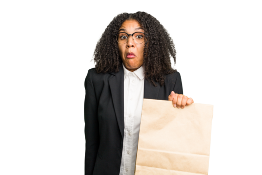 Young african american business woman holding a take away bag isolated shrugs shoulders and open eyes confused.
