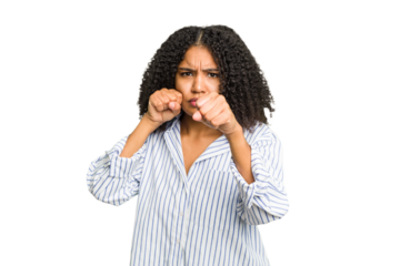 Young african american woman isolated throwing a punch, anger, fighting due to an argument, boxing.