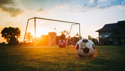 Silhouette action sport outdoors of kids kick soccer ball at green grass field under twilight...