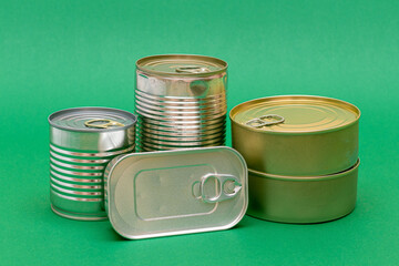 A Group of Stacked Tin Cans with Blank Edges on Green Background. Canned Food. Different Aluminum Cans for Safe and Long Term Storage of Food. Steel Sealed Food Storage Containers