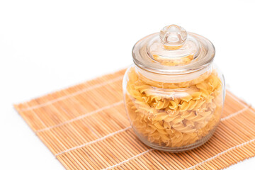 Uncooked Fusilli Pasta in Glass Jar on White Background. Raw and Dry Macaroni. Unhealthy and Fat...