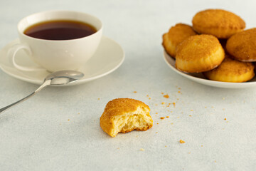 Delicious snack: a cup of black tea and a plate of cookies in close-up on a gray background.