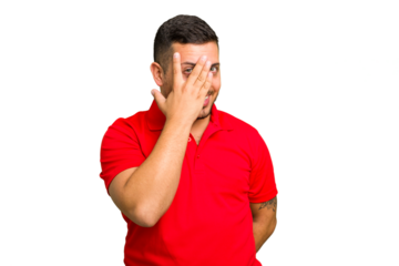 Young caucasian man isolated blink at the camera through fingers, embarrassed covering face.