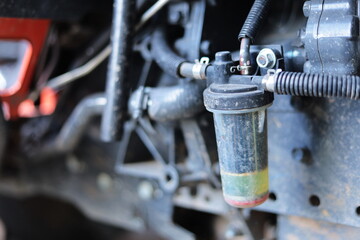 Old tractor oil filter. Oil filter hose in dirty diesel engine with black rubber hose attached to...