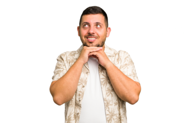 Young caucasian man isolated keeps hands under chin, is looking happily aside.