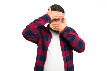 Young caucasian man isolated blink at the camera through fingers, embarrassed covering face.