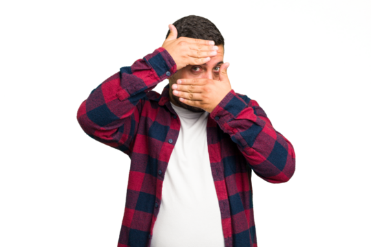 Young caucasian man isolated blink at the camera through fingers, embarrassed covering face.