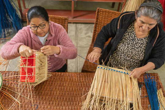 Hispanic craftswomen making straw baskets together