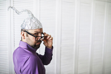 Bearded funny man in a cap of aluminum foil. Concept art phobias.Conspiracy theory. Conspiracy....