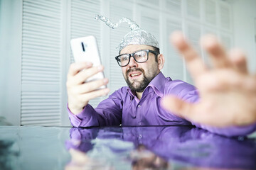 Bearded funny man in a cap of aluminum foil. Concept art phobias.Conspiracy theory. Conspiracy....