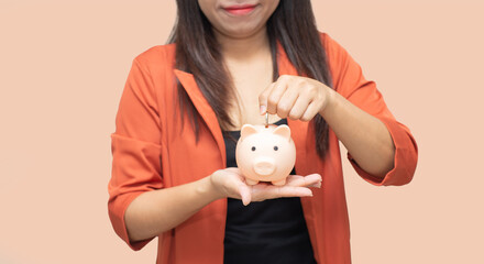 business woman hold piggy bank and putting coin with concrete wall for financial and saving money concept with pink concrete background and blank copy space.