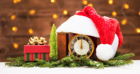 Christmas holidays banner with clock with santa hat and gift in box. Merry christmas and happy new year concept greeting card