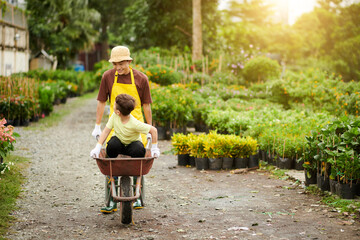 Father Pushing Wheelbarrow with Son Sitting inside