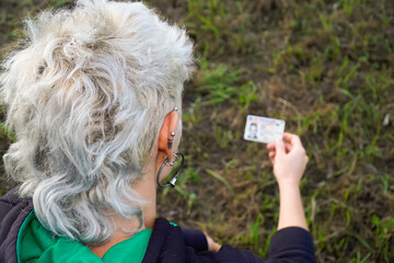 non-binary person looking at their new name on the identity card. rear view - Powered by Adobe