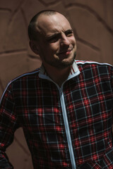 male portrait on the street in sunlight; dressed in a red and black suit