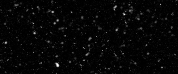 Falling snow isolated on black background. Falling snow at night. Bokeh lights on black background, flying snowflakes in the air. Winter weather. Overlay texture.