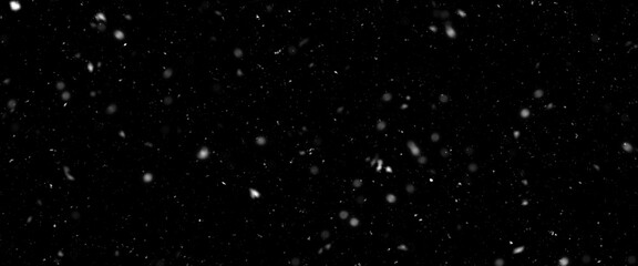 Falling snow isolated on black background. Falling snow at night. Bokeh lights on black background, flying snowflakes in the air. Winter weather. Overlay texture.
