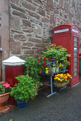 Flower pots and a phone booth next to a stone building in the town of Fortrose, on the Black Isle, in the Highlands of Scotland.