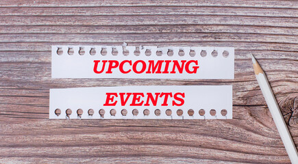 Background for text. White strips of paper with the text UPCOMING EVENTS and a white pencil next to it on a wooden background