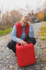 White woman in red vest holding red gasoline container and posing on scenic nature country road