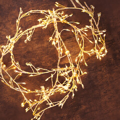  Christmas lights on a dark wooden background. Golden Xmas decorations sparkling garland top view, copyspace.