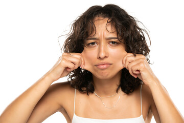 Fototapeta premium Portrait of young etnic woman, pulling her cheek skin on white background